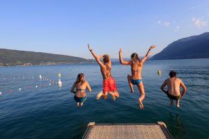 3 enfants sautent dans le Lac d'Annecy qui possède une plage accessible pour les personnes en situation de handicap