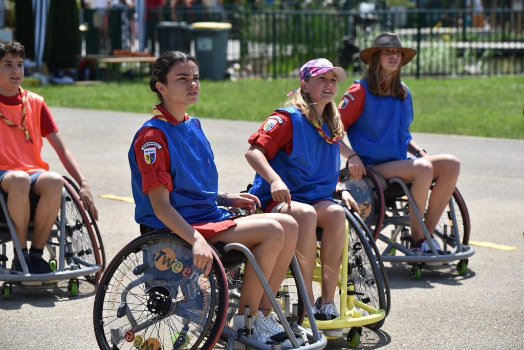 4 enfants essaient de faire du basket-fauteuil en atelier handisport. Sensibiliser les enfants au handicap par le sport.