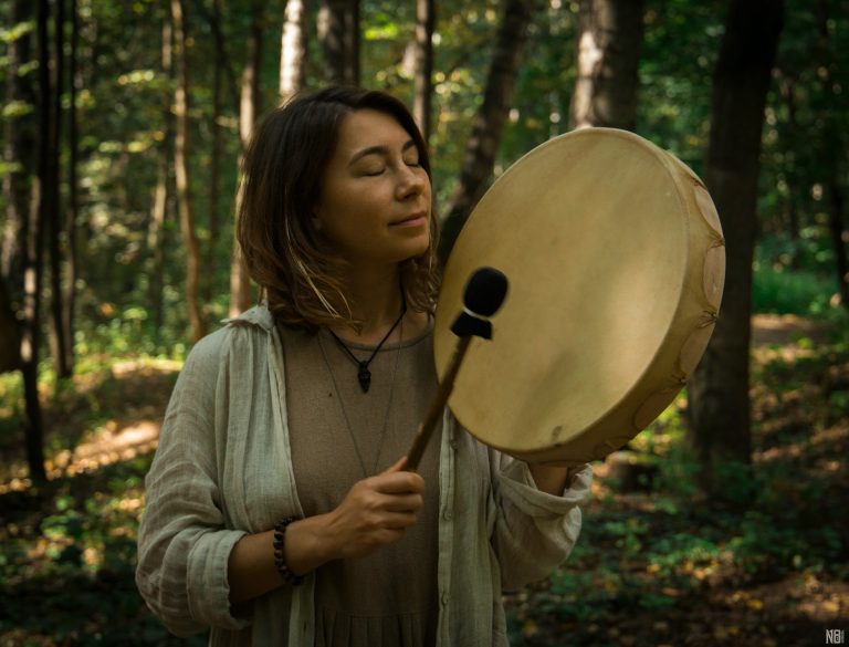 Une femme chamane tambourine un tambour dans les bois - l'autisme et le chamanisme